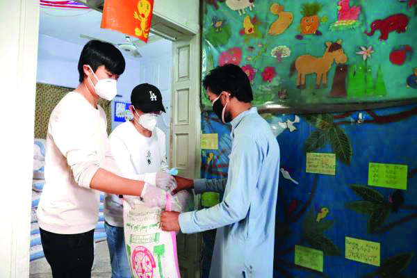 2020年4月15日，在巴基斯坦伊斯兰堡，马斌（左二）和志愿者（左一）向受到新冠疫情影响的当地居民发放生活物资。（新华社记者李浩摄）.jpg