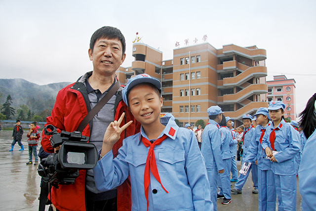 韩胜勋曾担任全国红军小学建设工程宣传部长，图为：作者与红军小学的学生合影.jpg